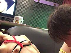 Miyuki tied on hotel sofa with AV playing.