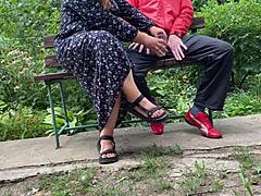 Hot mature MILF grabs huge cock for outdoor handjob. She milks cumshot into glass on park bench.