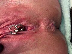 Why is this pierced clit getting rubbed hard in latex gloves before a strong pee stream?