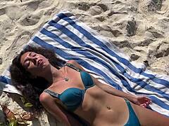 A shocked skinny babe in lingerie gets pissed on her oiled wet pussy at public beach pov