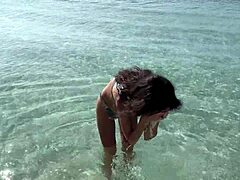 A shocked skinny babe in lingerie gets pissed on her oiled wet pussy at public beach pov